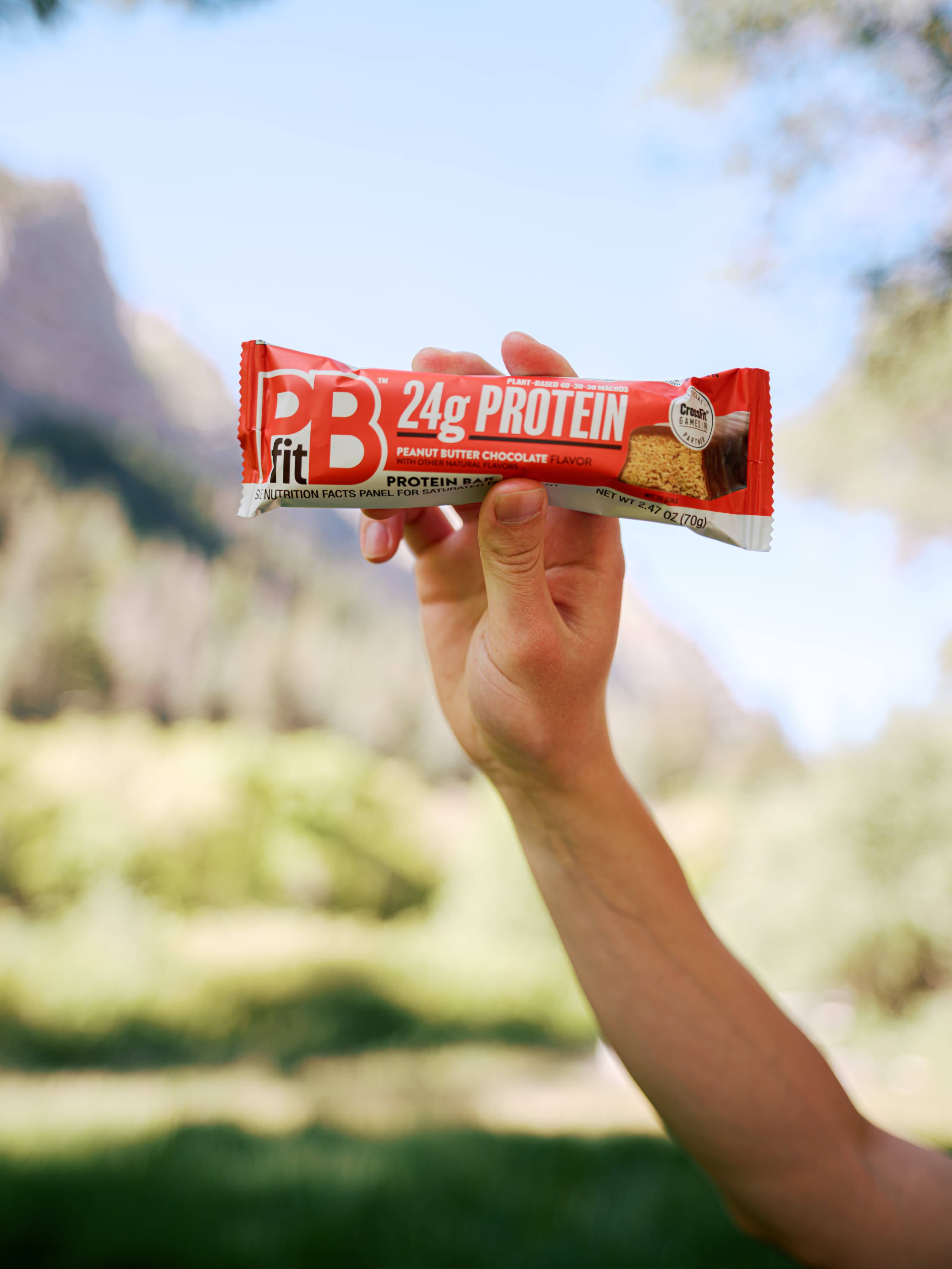 A PBfit protein bar held outdoors.